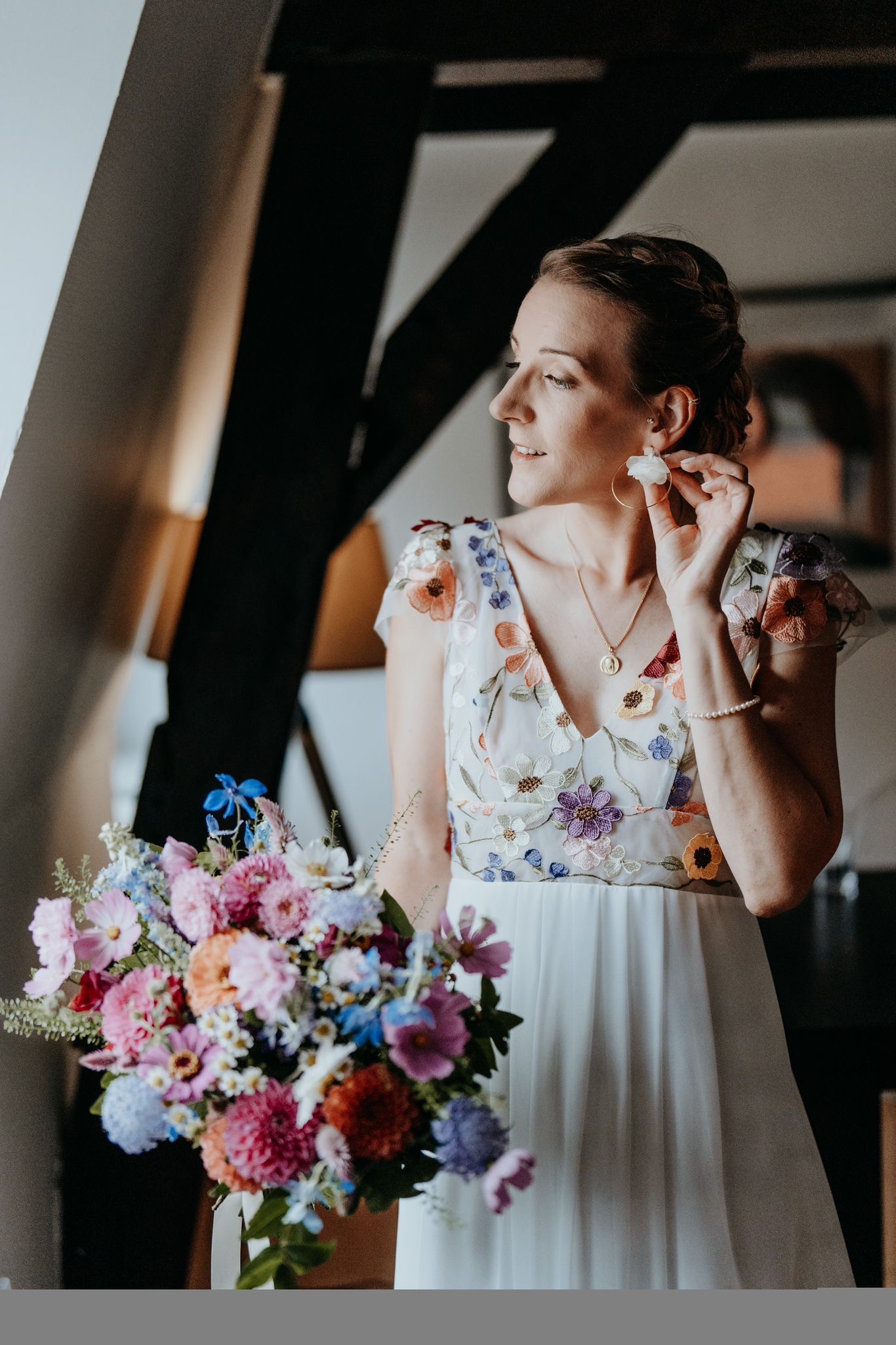 Mariée en robe fleurie ajustant ses boucles d'oreilles