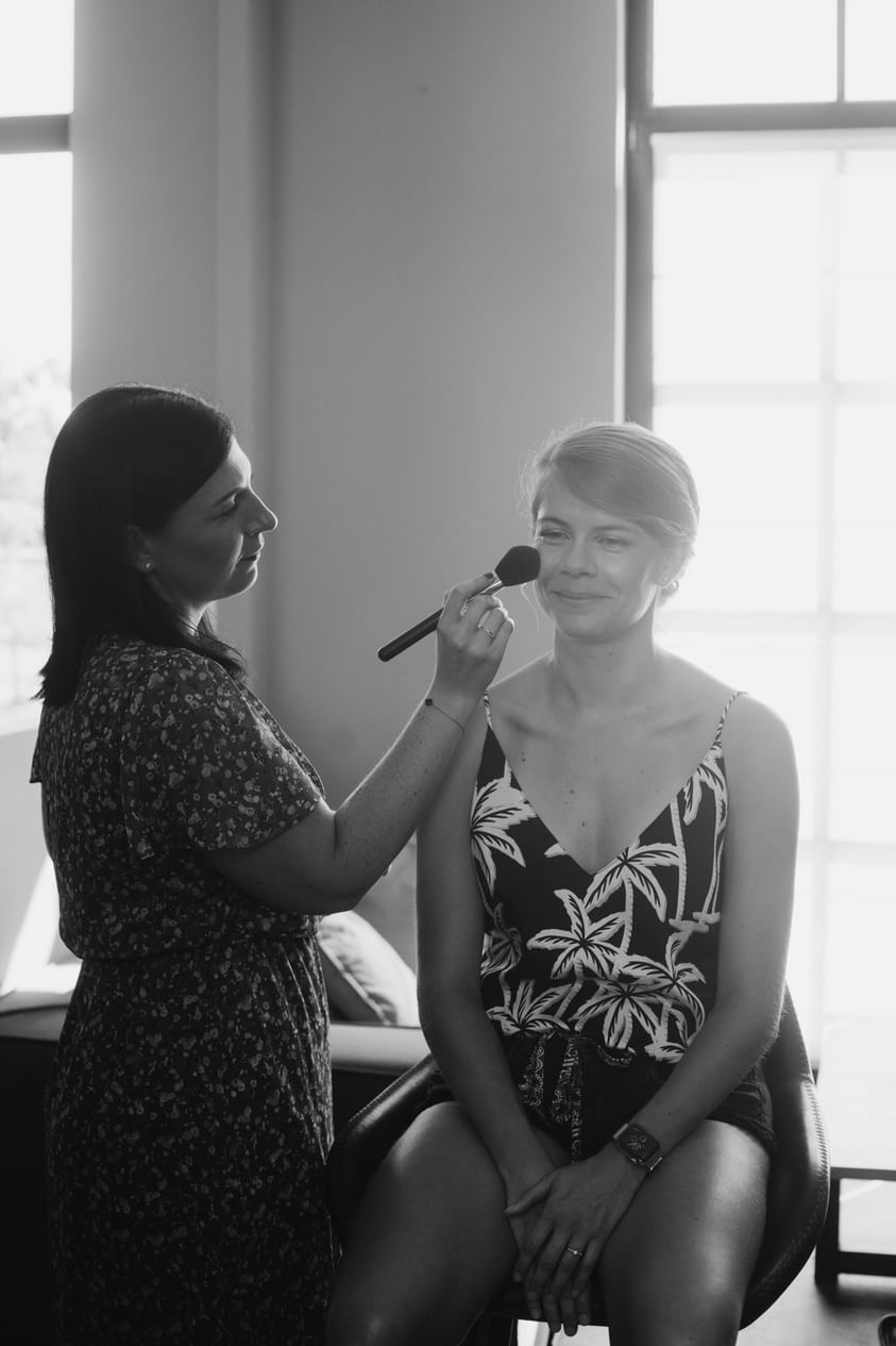 Kelly Clément appliquant le blush d'une cliente en lumière naturelle